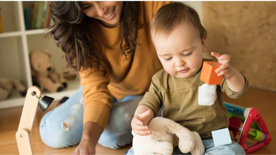 Une mère et son enfant jouant avec des jouets Montessori dans la chambre.