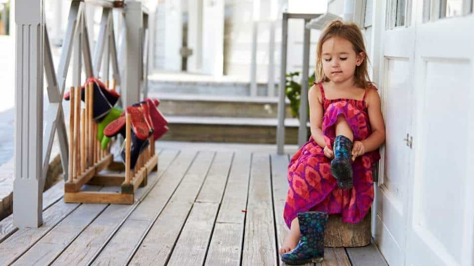 Une petite fille jouant en plein air sur le porche d'une maison, développant son autonomie et sa capacité d'initiative.